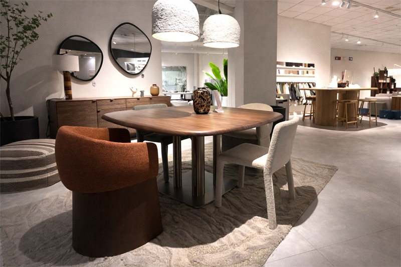 Comedor contempor&aacute;neo con mesa rectangular de madera oscura, sillas tapizadas en tonos neutros y terracota, aparador de madera y espejos redondos en la pared.